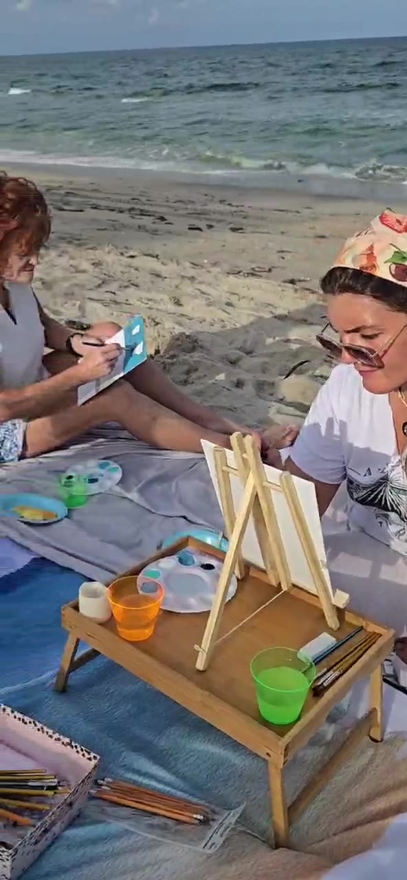Guests painting beside the ocean at an art picnic