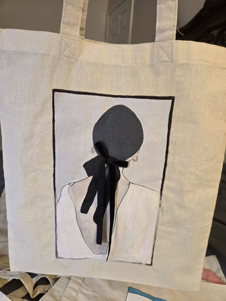 Canvas tote painted with a figure wearing a black ribbon