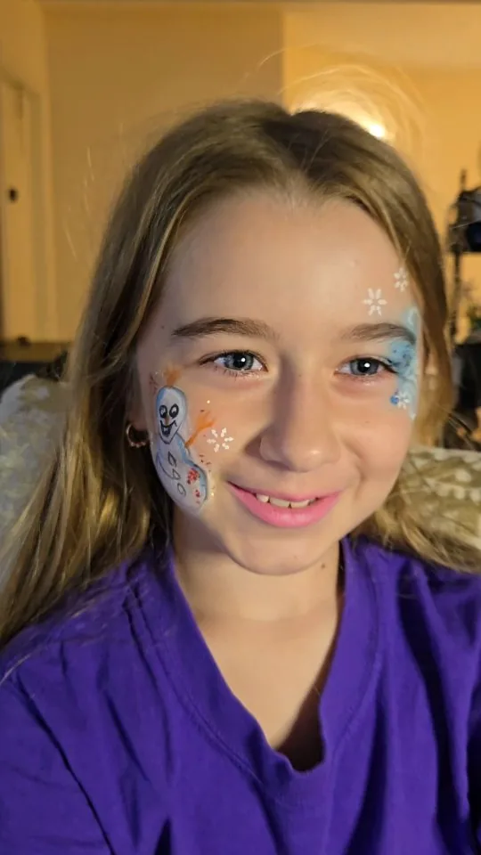 Winter-themed face paint with a snowman and snowflakes